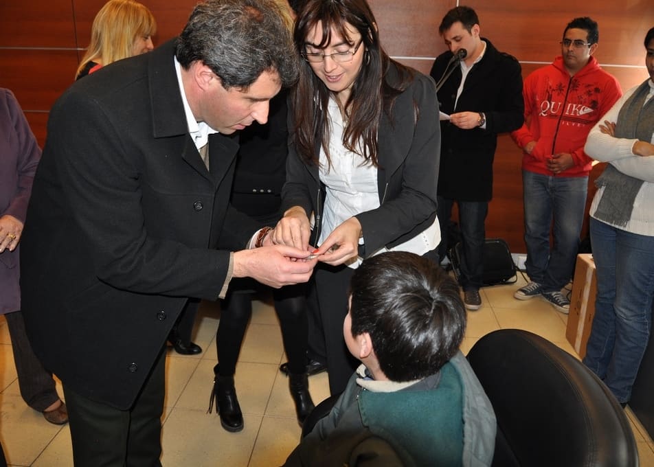 El vicegobernador, Sergio Uñac, hace entrega del equipo de audífonos a Juan Cruz de 12 años.